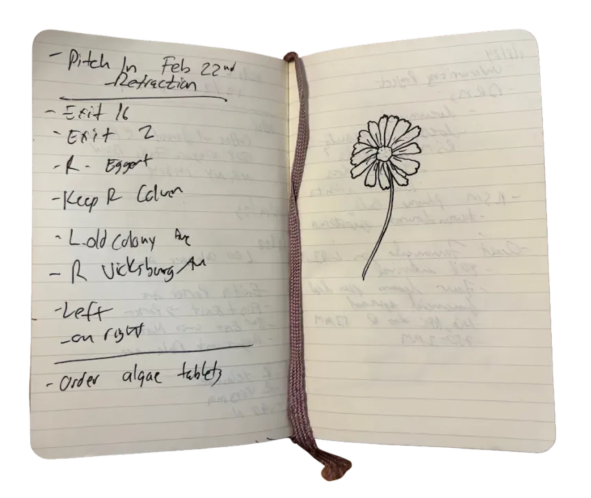 An open pocket notebook with directions written out by hand, exit numbers and street names down one page, and a daisy drawn on the other